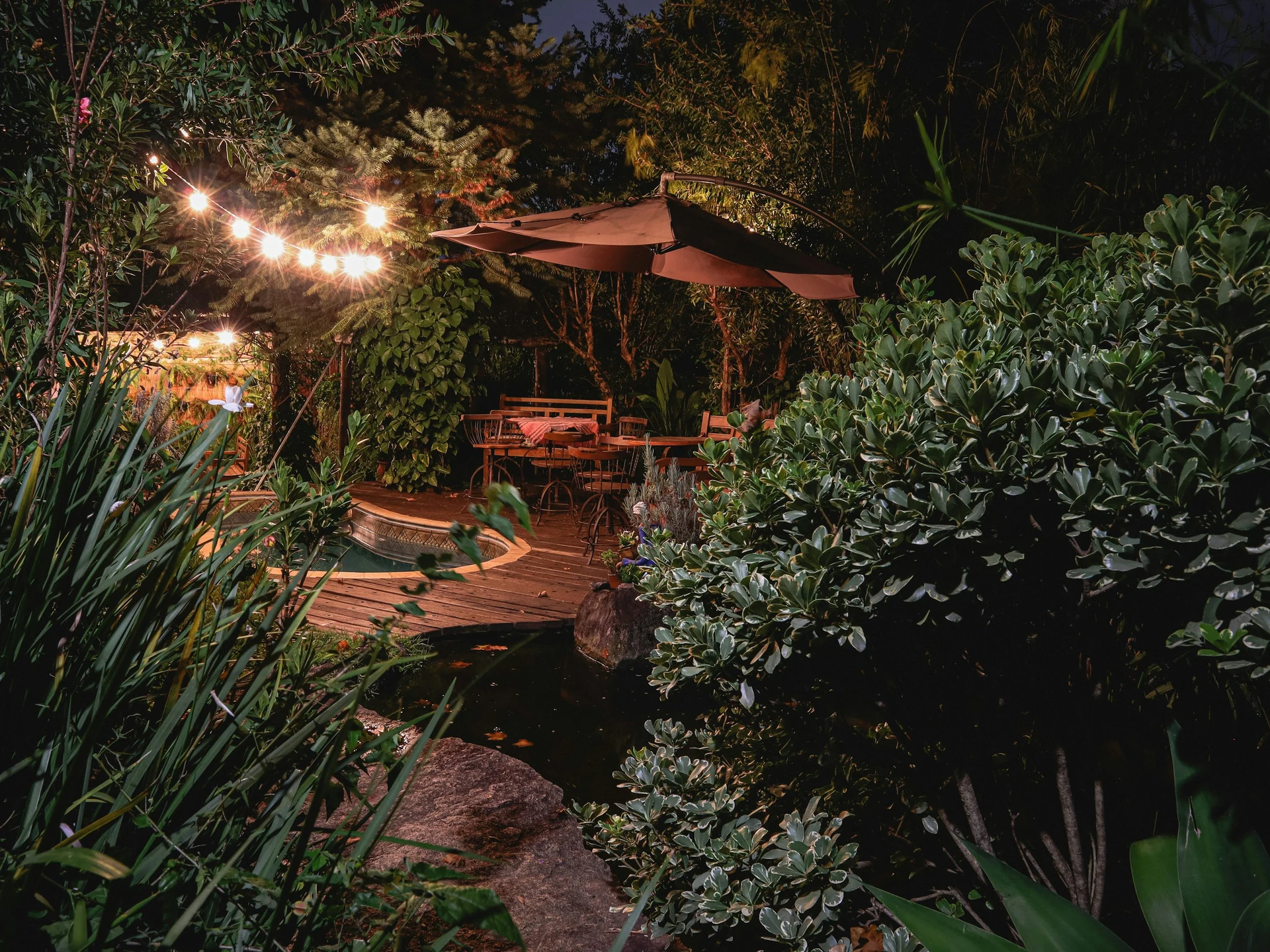 Warm beleuchteter Gartensitzplatz zwischen üppigen Pflanzen am Abend