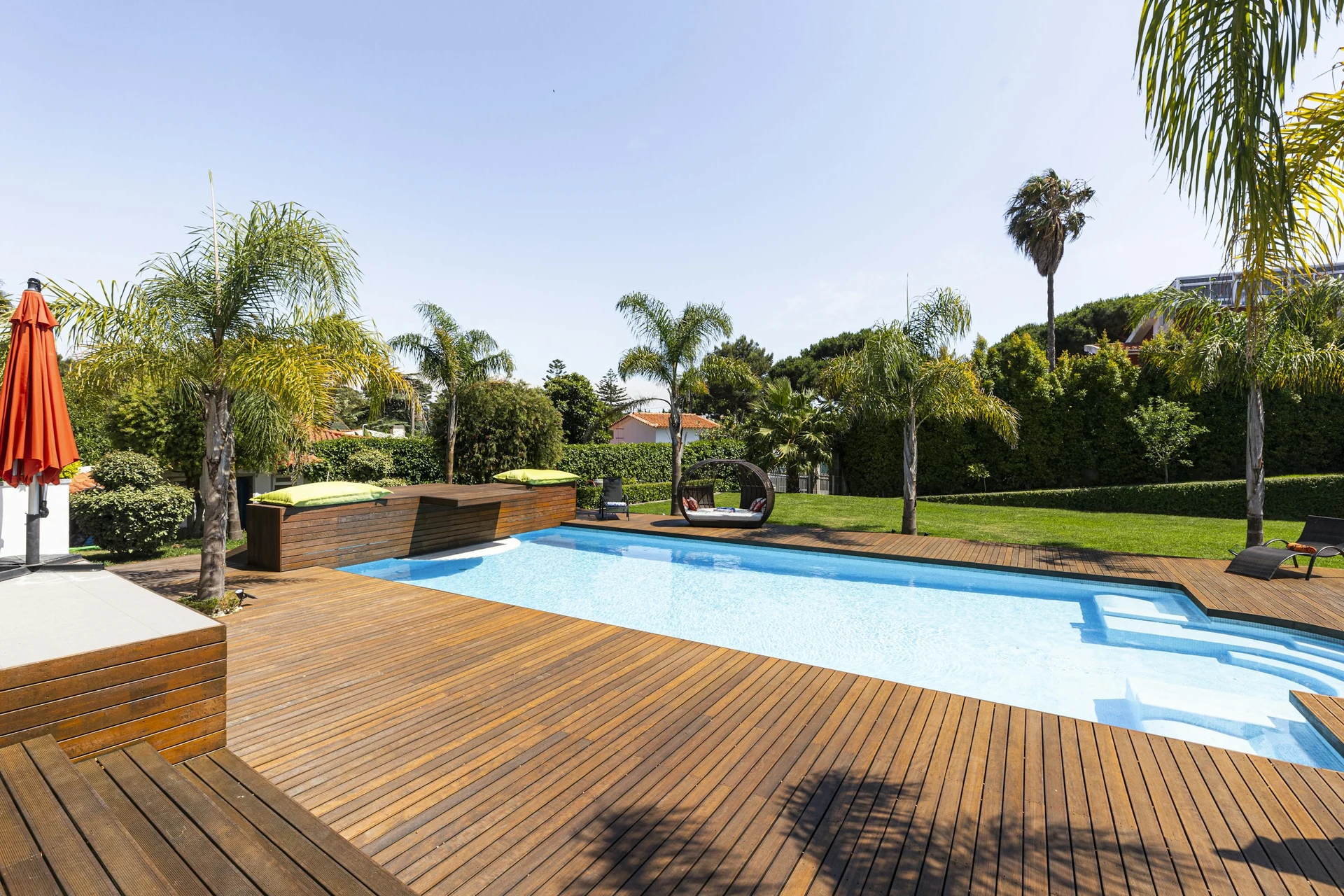 Pool mit breiter Holzterrasse und bepflanztem Garten