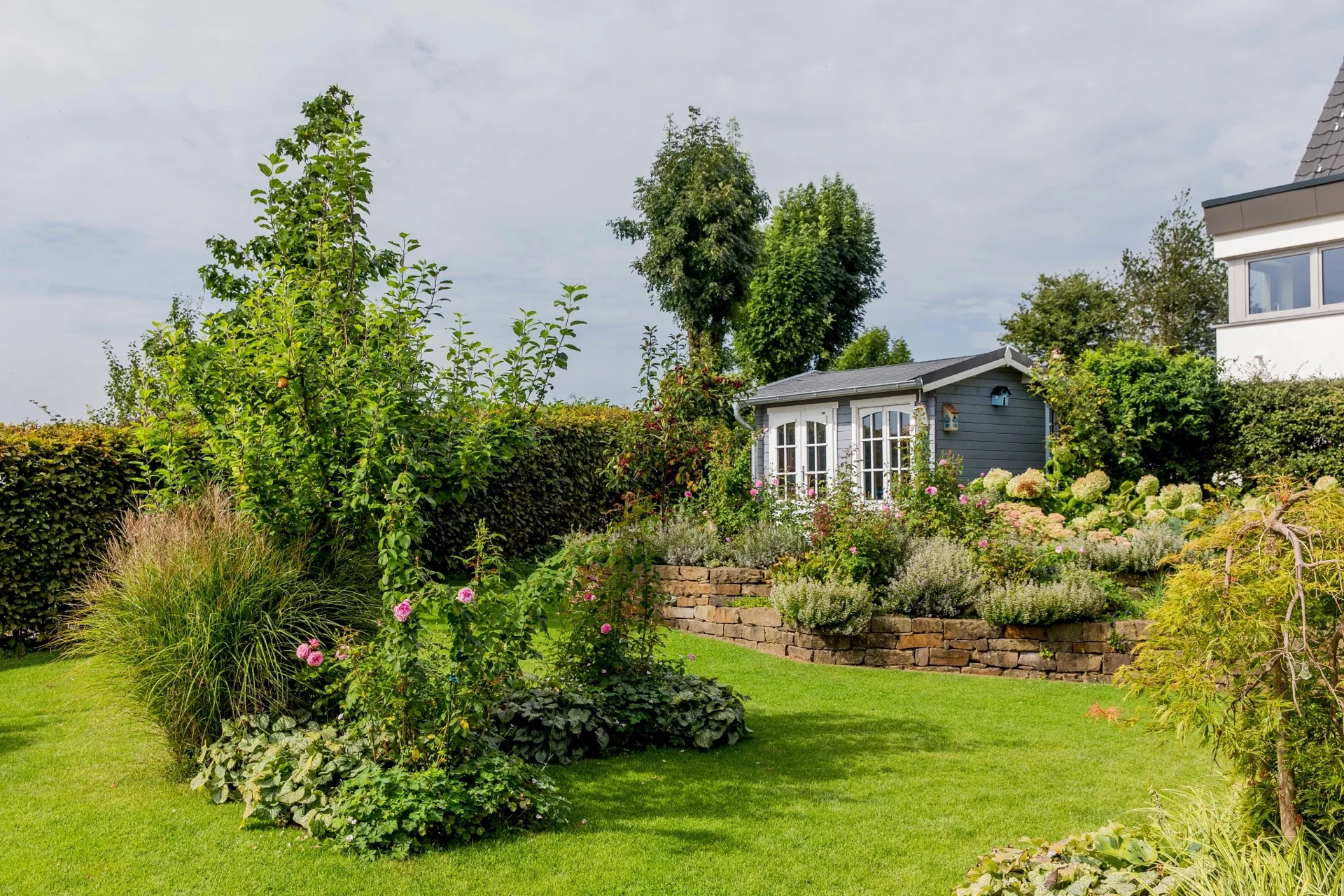 Garten mit Rasen, Stauden und Natursteinmauern