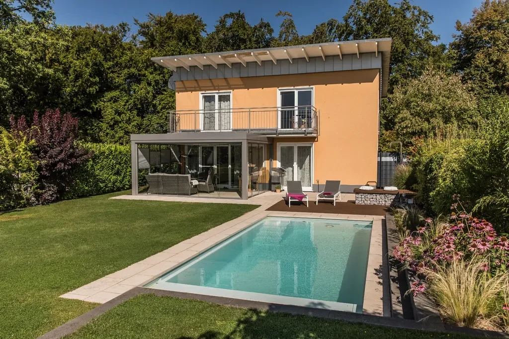 Rechteckiger Pool neben Terrasse und Wintergarten