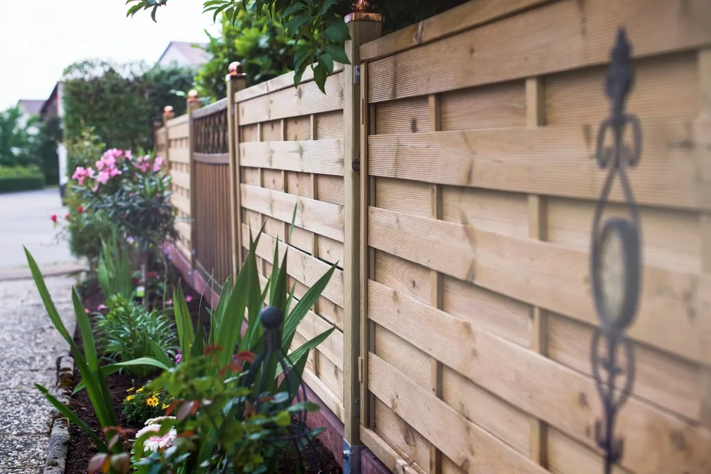Holzsichtschutz neben einem bepflanzten Gartenweg